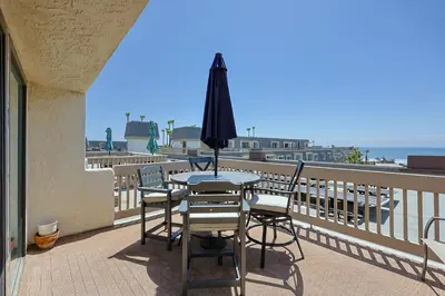 a table and chairs on a balcony with an umbrella at Oceanside Beach Condos in Oceanside