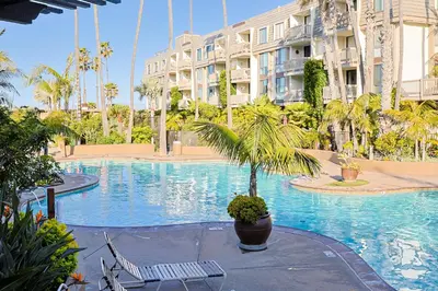 a large swimming pool with a palm tree in front of a building at Oceanside Beach Condos in Oceanside