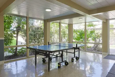 a ping pong table in a room with windows at Oceanside Beach Condos in Oceanside