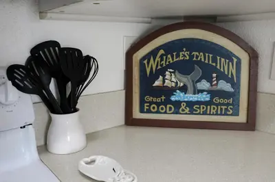 a kitchen counter with a vase with utensils and a sign at Oceanside Beach Condos in Oceanside