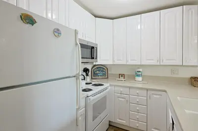 a kitchen with white cabinets and a white refrigerator at Oceanside Beach Condos in Oceanside
