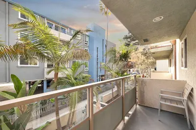 an apartment balcony with palm trees and a blue building at Central Location Villa - 2 blocks Mission Beach in San Diego