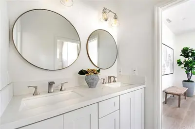 a white bathroom with two sinks and two mirrors at Situated in the heart of Costa Mesa near 17th Street in Costa Mesa