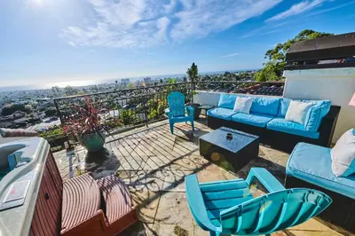 a patio with blue chairs and a couch on a balcony at Pool Hot Tubs Views - Castillo de Windsor in San Diego