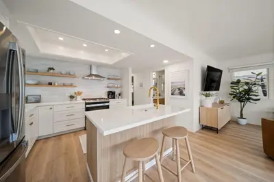 a kitchen with white cabinets and a island with two stools at Bayside Getaway Waterfront in Newport Beach