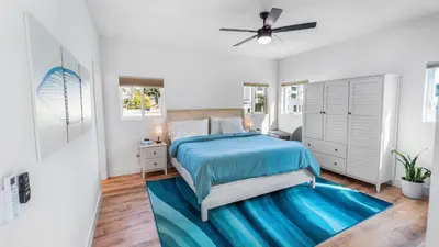 a white bedroom with a bed and a blue rug at Rise Suites Oceanside in Oceanside