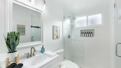 a white bathroom with a sink and a toilet at Coastal-Chic Newport Stay Steps to the Beach Dining Boardwalk Optional Add-On Unit in Newport Beach
