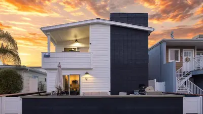 a white house with a sunset in the background at Coastal-Chic Newport Stay Steps to the Beach Dining Boardwalk Optional Add-On Unit in Newport Beach