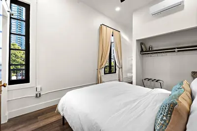 a white bedroom with a bed and two windows at The Artifact Hotel in San Diego