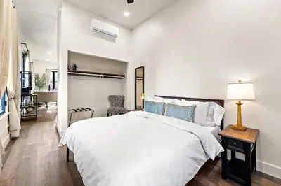 a white bedroom with a bed and a table with a lamp at The Artifact Hotel in San Diego