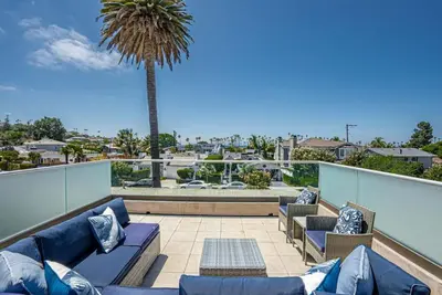 a patio with blue couches and a palm tree at La Jolla 3BR Oceanview Deck in San Diego