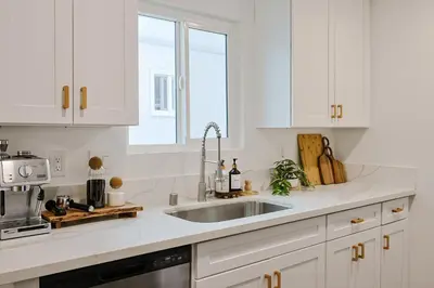 a white kitchen with a sink and a window at Immaculate Home near Balboa Park, SD Zoo, & Cafés in San Diego