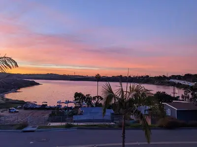 a sunset over a body of water with palm trees at Water Views on Every Floor for this multi Holiday Home - Walk to the Beach in Carlsbad