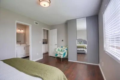a bedroom with a bed and a chair and a mirror at 15 Min from Torrey Pines State Beach and Golf in San Diego