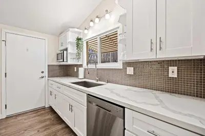 a white kitchen with white cabinets and a sink at 15 Min to Beach and Zoo - Hot Tub - Cozy Fire Villa Pit in San Diego