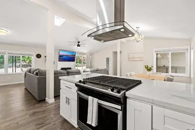 a kitchen and living room with a stove top oven at 15 Min to Beach and Zoo - Hot Tub - Cozy Fire Villa Pit in San Diego