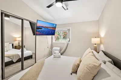 a bedroom with a bed and a tv on the wall at 15 Min to Beach and Zoo - Hot Tub - Cozy Fire Villa Pit in San Diego