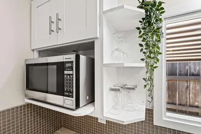 a kitchen with a microwave in a white kitchen at 15 Min to Beach and Zoo - Hot Tub - Cozy Fire Villa Pit in San Diego