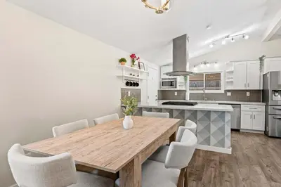 a kitchen with a wooden table and white cabinets at 15 Min to Beach and Zoo - Hot Tub - Cozy Fire Villa Pit in San Diego