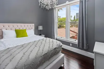 a bedroom with a bed with a chandelier and a window at 1900's Victorian Home Sleeps 22 8BDRM 3Bath in San Diego