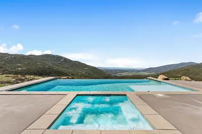 a swimming pool with blue water and mountains in the background at nmc in Descanso