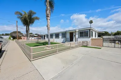 a house with a fence and a palm tree at 2 Homes in 1 Sleeps 18 10 Min to Zoo and Beach in San Diego