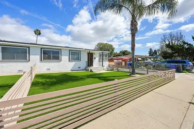 a fence in front of a house with a palm tree at 2 Homes in 1 Sleeps 18 10 Min to Zoo and Beach in San Diego