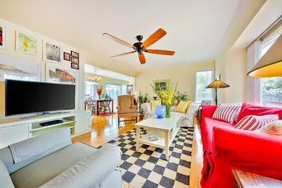 a living room with a red couch and a flat screen tv at Sunny Gardens A Classic La Jolla Beach Home Close to Wind n Sea Beach in San Diego
