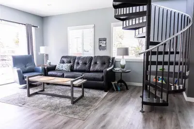 a living room with a couch and a spiral staircase at Sunrise Loft in San Diego