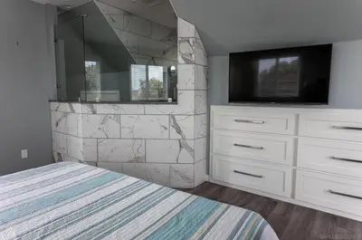 a bedroom with a bed and a tv and a stone wall at Sunrise Loft in San Diego