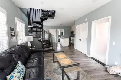 a living room with a leather couch and a spiral staircase at Sunrise Loft in San Diego