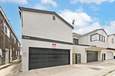 a white house with two garage doors in a driveway at Spacious Oceanfront Home Near Newport Pier in Newport Beach
