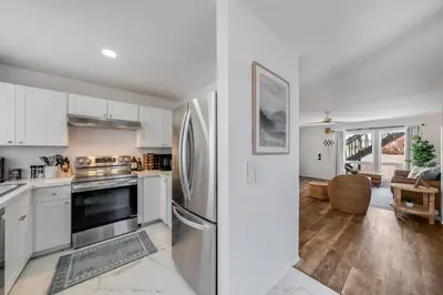 a kitchen with white cabinets and a stainless steel refrigerator at BoHo Beach House Walk to the Sand in San Diego