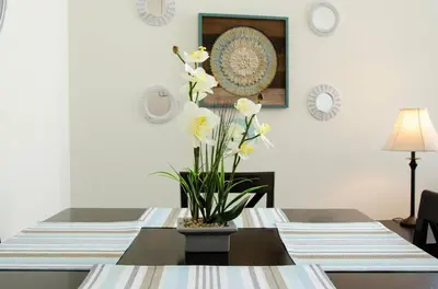 a dining room table with a vase of flowers on it at Charming 3 Bedroom Apartment with Pool Near San Diego Convention Center in San Diego