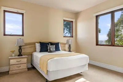 a bedroom with a white bed and two windows at 7BR Carlsbad Estate with Pool Firepit & Views in Carlsbad