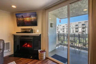 a living room with a fireplace and a balcony at Walk to the Beach Pool & Hot Tubs & Gym - A-116 in Oceanside
