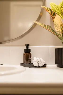 a bathroom sink with a bottle of soap and a mirror at Upscale Modern Spacious Loft in Little Italy in San Diego