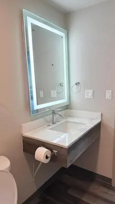a bathroom with a sink with a mirror and a toilet at Broadway Inn and Suites in Chula Vista