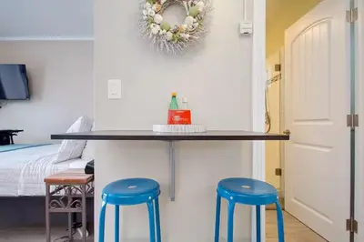a table with two blue stools next to a bedroom at Steps to Newport Harbor Balboa Fun Zone Dock Access Edgewater Studios in Newport Beach