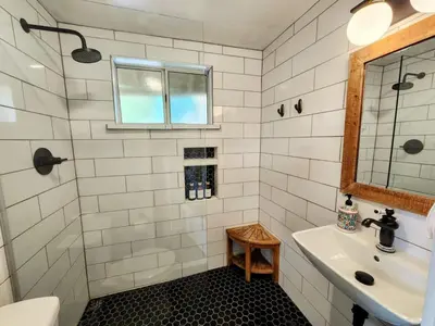 a white tiled bathroom with a sink and a window at Urban Oasis Near Downtown & Balboa Park in San Diego