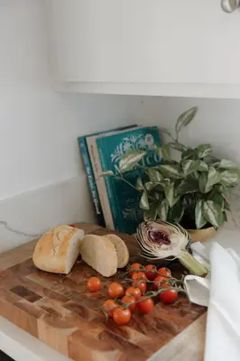 a cutting board with tomatoes and bread and a book at Designer Bungalow Steps to Beach in San Diego