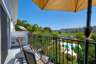 a balcony with chairs and an umbrella and a pool at Pool, Hot Tub, Steps To Omni La Costa in Carlsbad