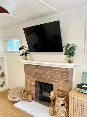 a living room with a tv above a brick fireplace at Casa Sol in San Diego