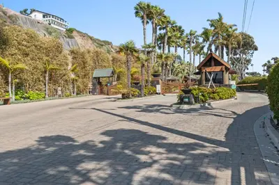 a street with palm trees and a house on a hill at Private beach toes on the Sand Waterworld in Dana Point