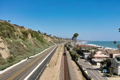 an empty highway next to the ocean with palm trees at Private beach toes on the Sand Waterworld in Dana Point