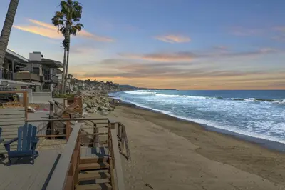 a beach with chairs and palm trees and the ocean at Private beach toes on the Sand Waterworld in Dana Point