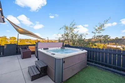 a hot tub on a patio with a fence at Dog-Friendly House with Hot Tub, AC, Game Room in Oceanside