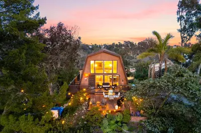 a house in the middle of a forest at sunset at The SeaBarn Vista Views, Hot Tub and Stargazing in San Diego