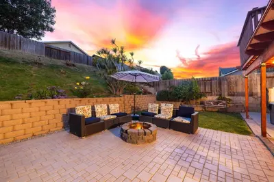 a patio with couches and a fire pit with a sunset at Spacious 4BR Oasis with Pool Table and Spa in San Diego