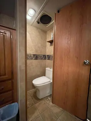 a bathroom with a toilet and a wooden door at La Mesa Cozy Camper in San Diego
